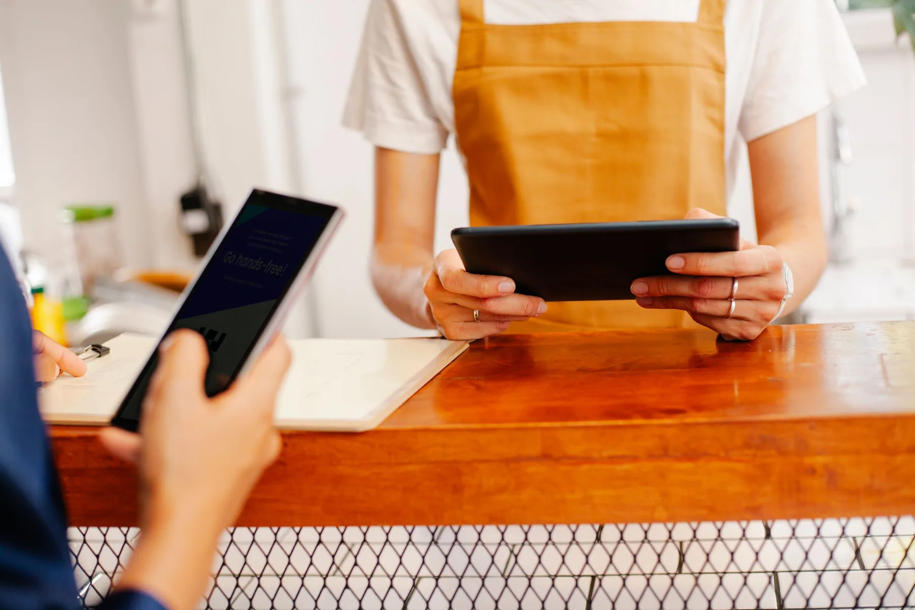 A small-business team using a phone and tablet together at the counter.
