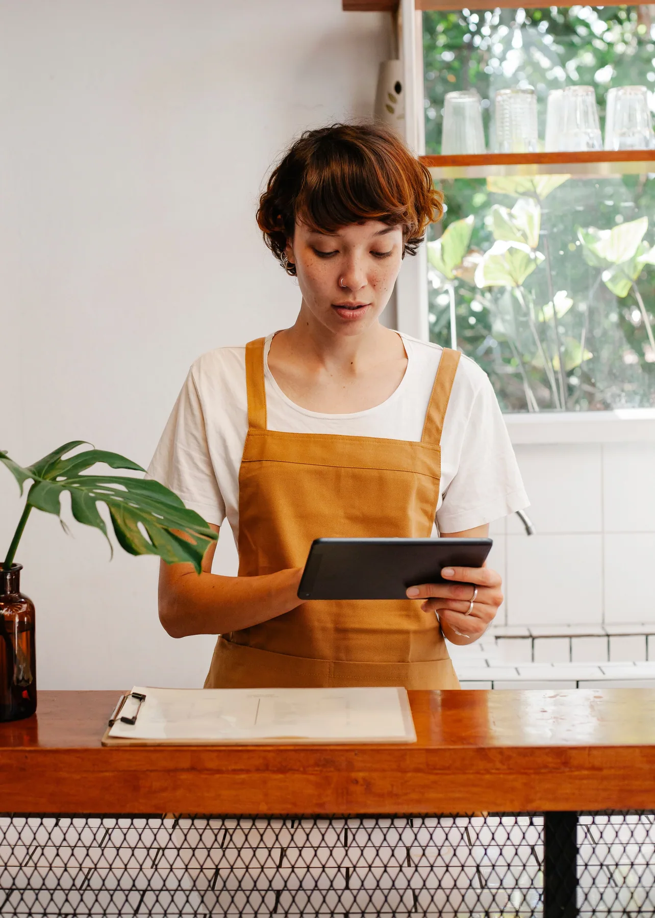 A small-business owner using a tablet behind the counter.