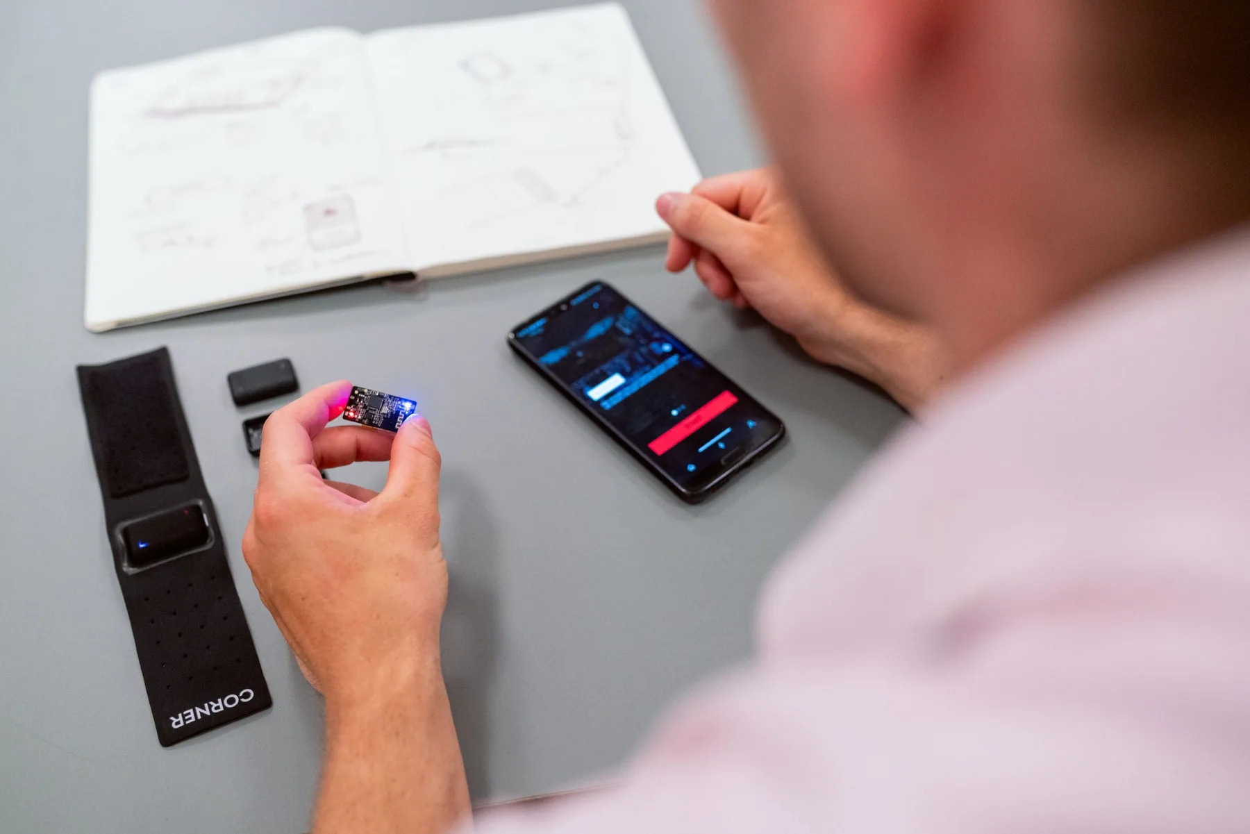 An engineer testing a wearable product prototype with a smartphone.