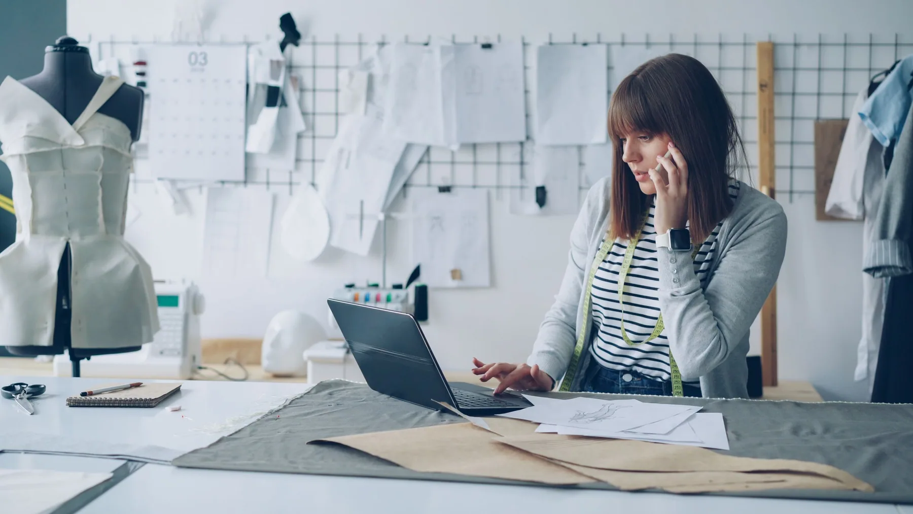 A designer developing ideas among sketches, materials and a studio mannequin.