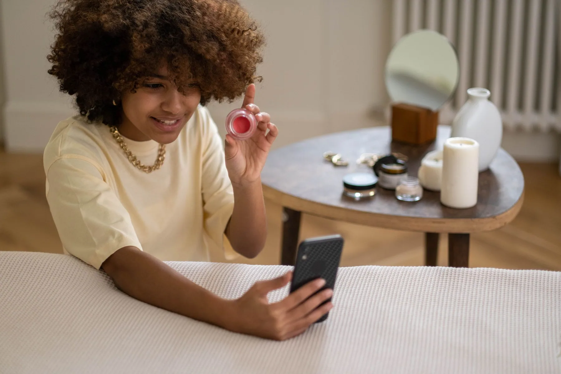 A content creator filming a product with a smartphone and studio lighting.